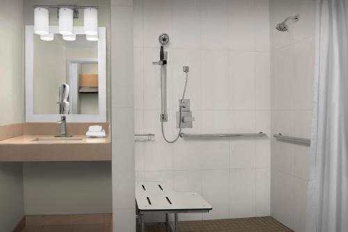 a bathroom with a shower with a bench and a sink at TownePlace Suites Sacramento Cal Expo in Sacramento