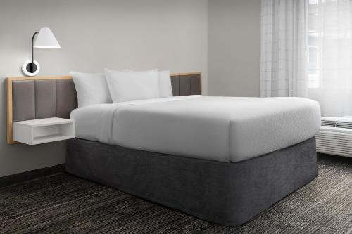 a bedroom with a large white bed with a lamp at TownePlace Suites Sacramento Cal Expo in Sacramento