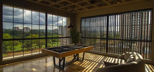 a living room with a table in a room with large windows at Blend Coliving One - 2b in Ribeirão Preto