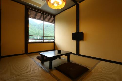 a room with a table in front of a window at Tabinoyado Asonoyu in Aso