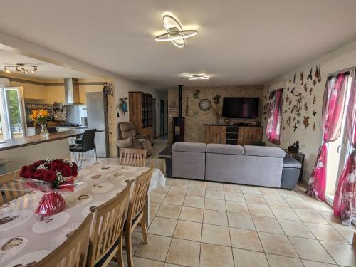 a kitchen and living room with a table and a couch at Titre proposé : Gîte familial avec piscine chauffée, jardin et jeux pour enfants à l'orée de la forêt d'Orléans - FR-1-590-432 in Mareau-aux-Bois