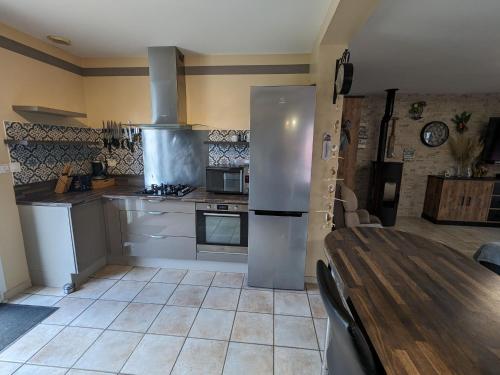 a kitchen with a wooden table and a refrigerator at Titre proposé : Gîte familial avec piscine chauffée, jardin et jeux pour enfants à l'orée de la forêt d'Orléans - FR-1-590-432 in Mareau-aux-Bois