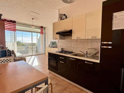 - une cuisine avec un évier et un comptoir avec une table dans l'établissement Appartement rénové 2 pièces 4 pers avec jardin privatif - Plage à 2 pas - Port-la-Nouvelle - FR-1-229C-95, à Port-la-Nouvelle