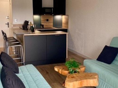 un salon avec un canapé bleu et une cuisine dans l'établissement Studio Rénové et Climatisé avec Terrasse, Parking Privé et Options Confort à Marseillan - FR-1-387-209, à Marseillan