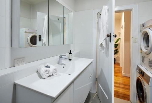 La salle de bains blanche est pourvue d'un lavabo et d'un lave-linge. dans l'établissement 1 Bedroom Art Deco Apt With Study, à Prahran