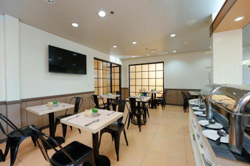 un restaurante con mesas y sillas y TV en la pared en Microtel by Wyndham Davao en Davao