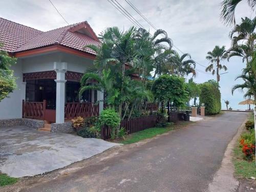 a house with palm trees and a driveway at บ้านทรายแก้ว in Ban Phlong Sawai