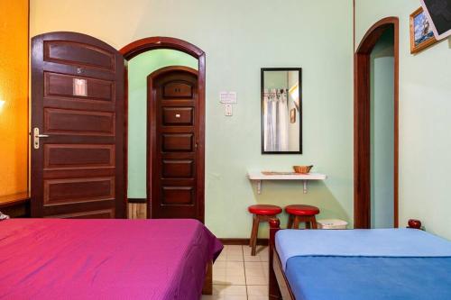 a bedroom with two beds and a door and two stools at Suítes Casa Verde in Arraial do Cabo