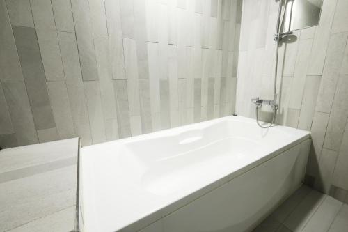 a white bathroom with a tub and a shower at Ignis Hotel busan sports complex branch in Busan