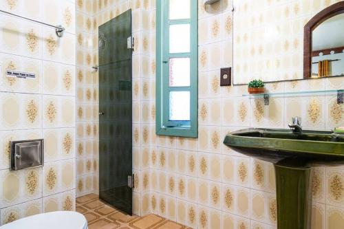 a bathroom with a green sink and a mirror at Suítes Casa Verde in Arraial do Cabo