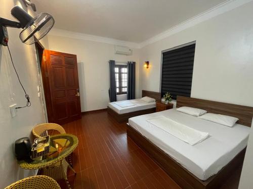 una camera con due letti e un tavolo con sedie di Hotel Me Kong 2 a Ha Long