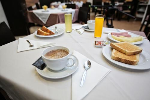 a table with a cup of coffee and bread and toast at Hotel Recinto in Fátima