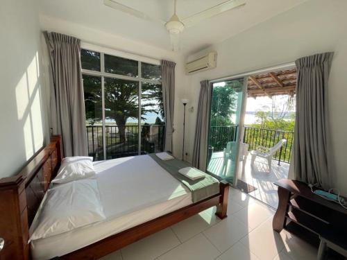 a bedroom with a bed and a balcony at My Beach Villa in Port Dickson