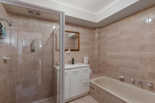 La salle de bains est pourvue d'une baignoire, d'un lavabo et d'une douche. dans l'établissement By The Sea Beachfront Apartment Wifi, à Encounter Bay