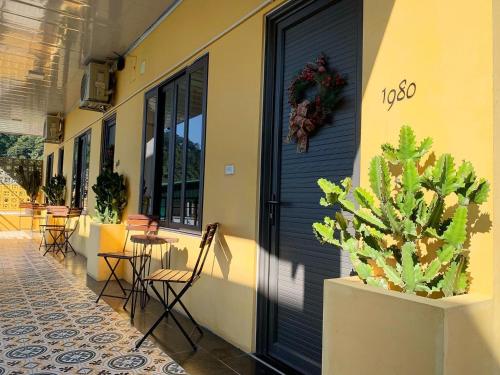 a building with a black door and a table and chairs at Ầu ơ Homestay - Venuestay in Tam Ðảo
