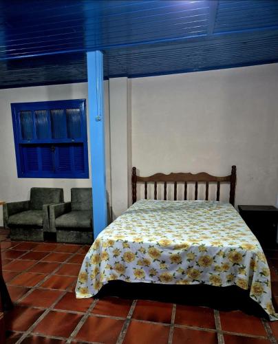 a bedroom with a bed and two chairs in it at Pousada Vino & Leta O seu parador no centro in Grão Pará