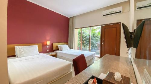 Habitación de hotel con 2 camas y ventana en Lorin Dwangsa Solo Hotel en Solo