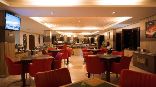 a restaurant with tables and chairs and a kitchen at Lorin Dwangsa Solo Hotel in Solo