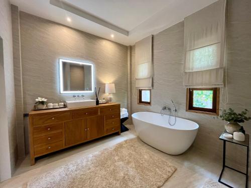 een badkamer met een bad, een wastafel en een spiegel bij Moorea Boutique Resort Samui in Koh Samui 