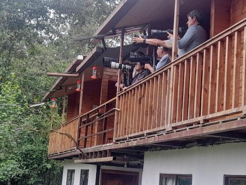 a group of people sitting on the balcony of a house at Sendero de las aves in Mindo