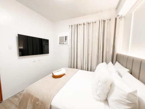 a white bedroom with a bed and a television at AZRA Bacolod at Mesavirre Garden Residences in Bacolod