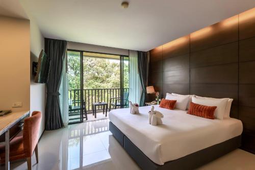 a bedroom with a large bed with a desk and a balcony at Aree Tara Ao Nang Krabi in Ao Nang Beach