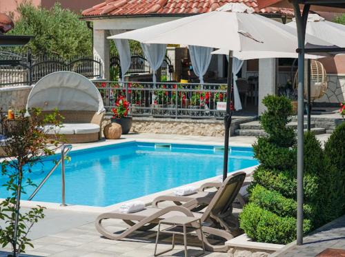 een zwembad met 2 ligstoelen en een parasol bij Apartments Antonia in Šibenik