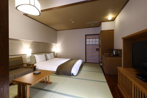 a hotel room with a bed and a television at Inishie no Yado Keiun in Izumo