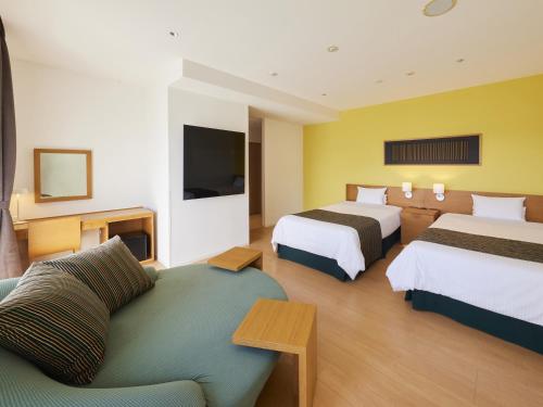 een hotelkamer met 2 bedden en een bank bij Hotel Rotterdam Huis Ten Bosch in Sasebo