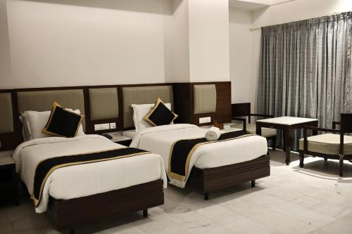 ein Hotelzimmer mit 2 Betten und einem Tisch in der Unterkunft Hotel Saratharajans in Madurai