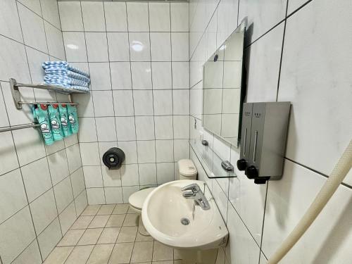 un bagno bianco con lavandino e specchio di Xingang Homestay a Xingang
