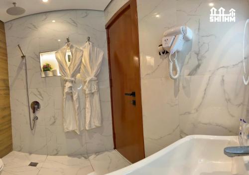 a bathroom with a tub and a shower with a robe at شقق شهم المفروشه in Abha