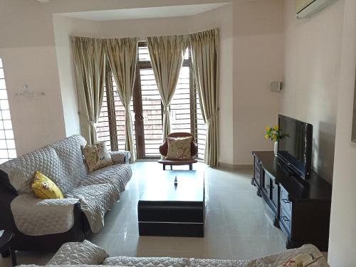 a living room with a couch and a tv at Eden Nomad Living in Batu Ferringhi