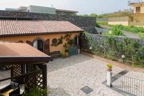 a house with a stone wall and a patio at B&B Villa Liliya in Fiumefreddo di Sicilia