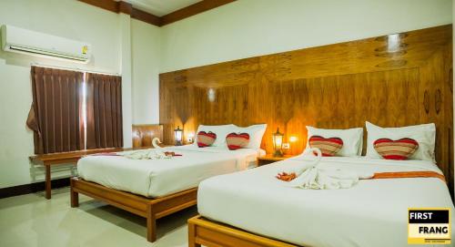 1 dormitorio con 2 camas con sábanas blancas y almohadas rojas en First and Frang Hotel - Koh Phangan en Thongsala