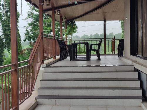 a porch with two chairs and a table on it at Raj Heritage in Murbād