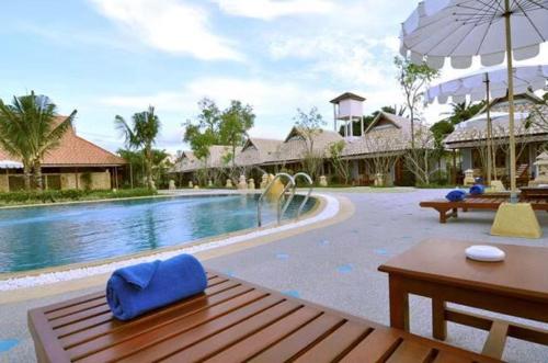 a swimming pool with a wooden table and an umbrella at Ongsantiphap villa resort in Ban Klang