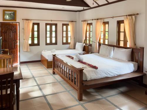 a bedroom with two beds and a desk and windows at Ongsantiphap villa resort in Ban Klang