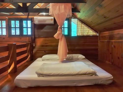 two beds in a room with wooden walls at Muangkham Cabin in Chiang Mai