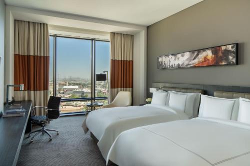 リヤドにあるFairmont Riyadhのベッド2台とデスクが備わるホテルルームです。