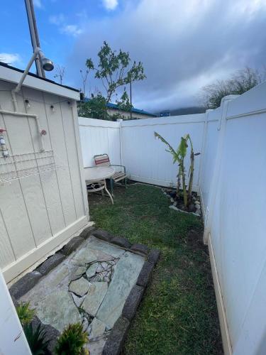a backyard with a white fence and a bench at Robbins Estate in Wailuku