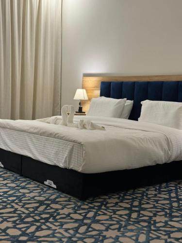 a large bed with white sheets and a blue headboard at ضيف بارك للشقق المخدومة in Ad Dawādimī