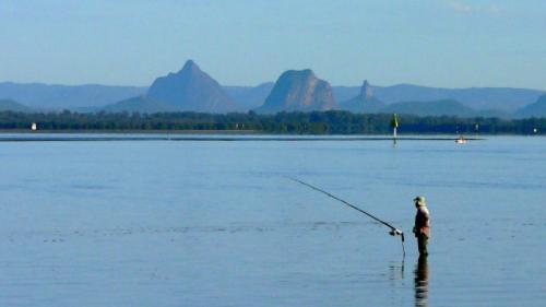 a man standing in the water holding a fishing rod at Bella Cove in Bellara