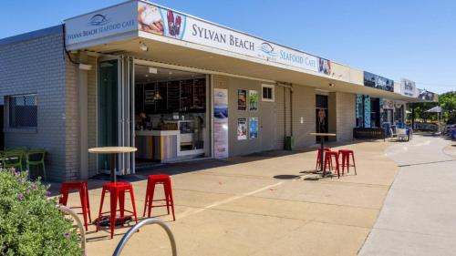 a group of red stools in front of a store at Bella Cove in Bellara