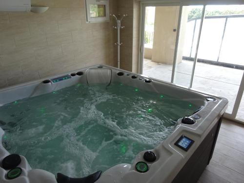 uma grande banheira de hidromassagem num quarto em gite la bonnelle piscine spa em Grillon