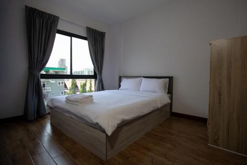 a bedroom with a bed and a large window at Room 36 service apartment in Bangkok