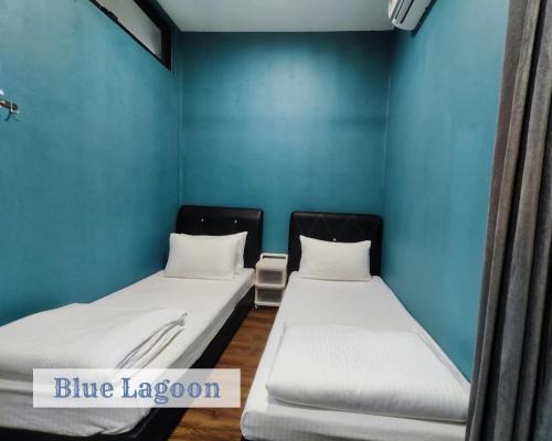 two beds in a room with blue walls at Roxy Sematan Townhouse - Blue Lagoon in Sematan