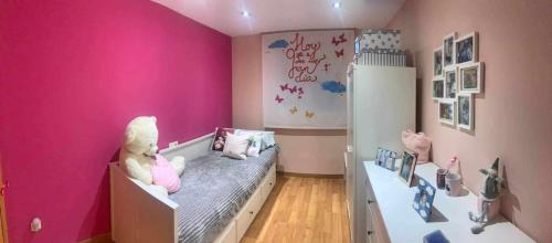 une chambre d'enfant avec des murs roses et un lit avec un ours en peluche dans l'établissement Puerto de Sagunt America 39, à Puerto de Sagunto