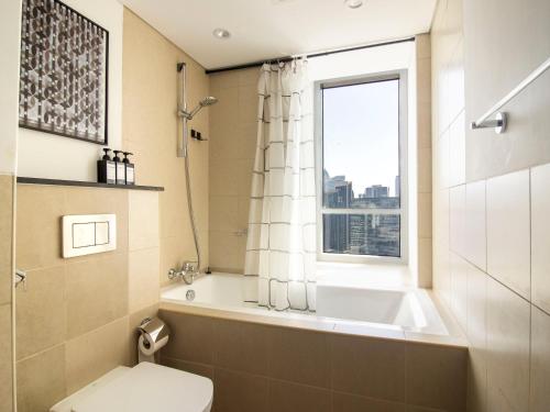 uma casa de banho com uma banheira, um WC e uma janela. em Downtown Chic Easy walk to Dubai Mall & Fountain no Dubai