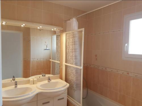 une salle de bain avec deux lavabos, un miroir et une baignoire dans l'établissement Villa del Sol, au Barcarès